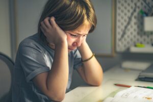 upset schoolgirl doing lessons, her homework. learning difficulties