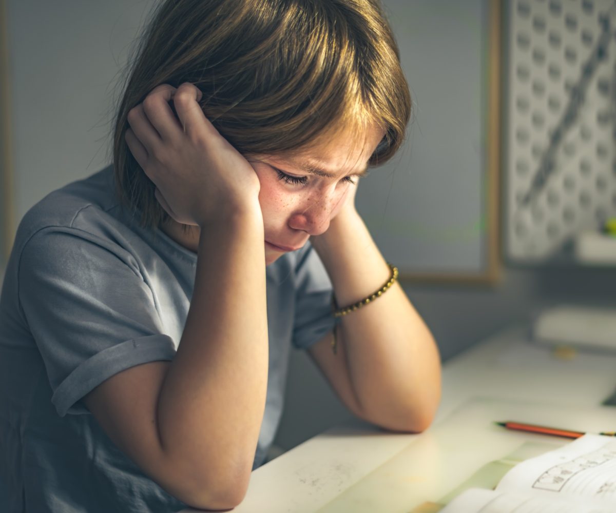 upset schoolgirl doing lessons, her homework. learning difficulties